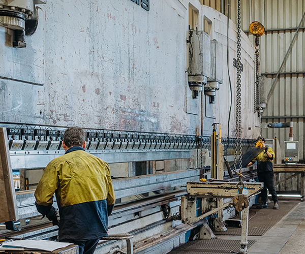 Men operating a huge pressingmachine for steel